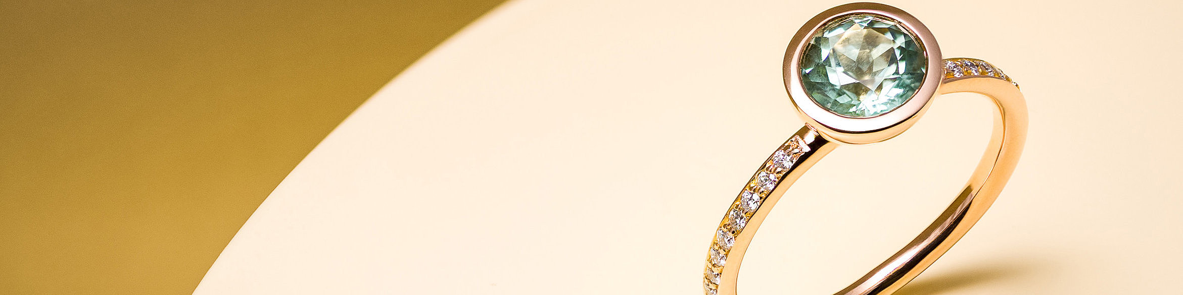 Rotgoldener Ring mit grünem Turmalin in einer Zarge mit vielen Brillanten